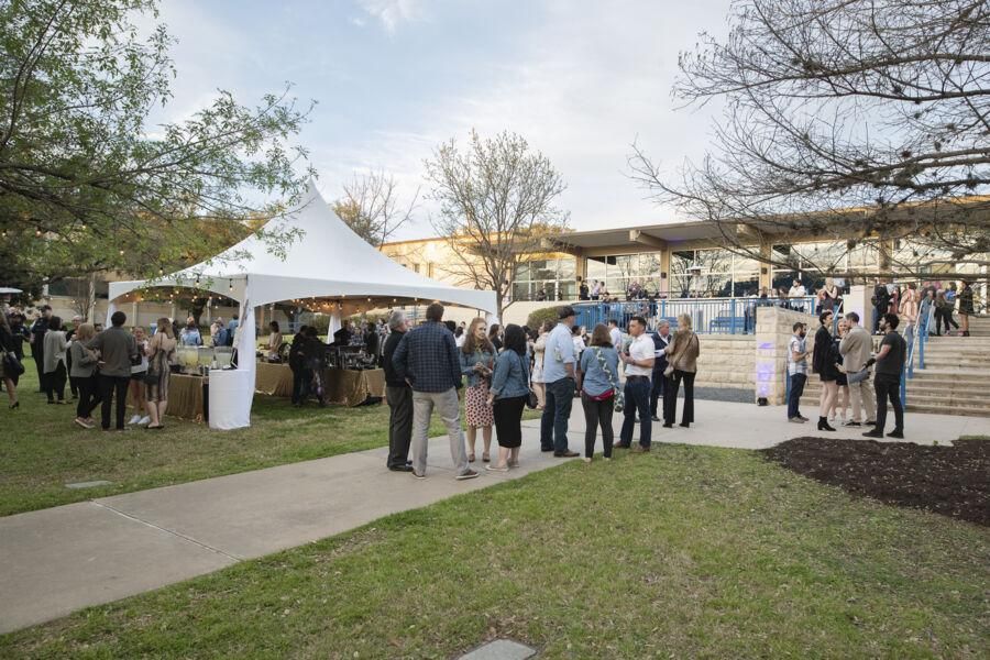 People mill around a tented reception outside the Fine Arts Center.