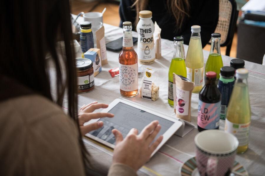 A graduate student takes notes on her iPad as her and her team discuss food products on the table.