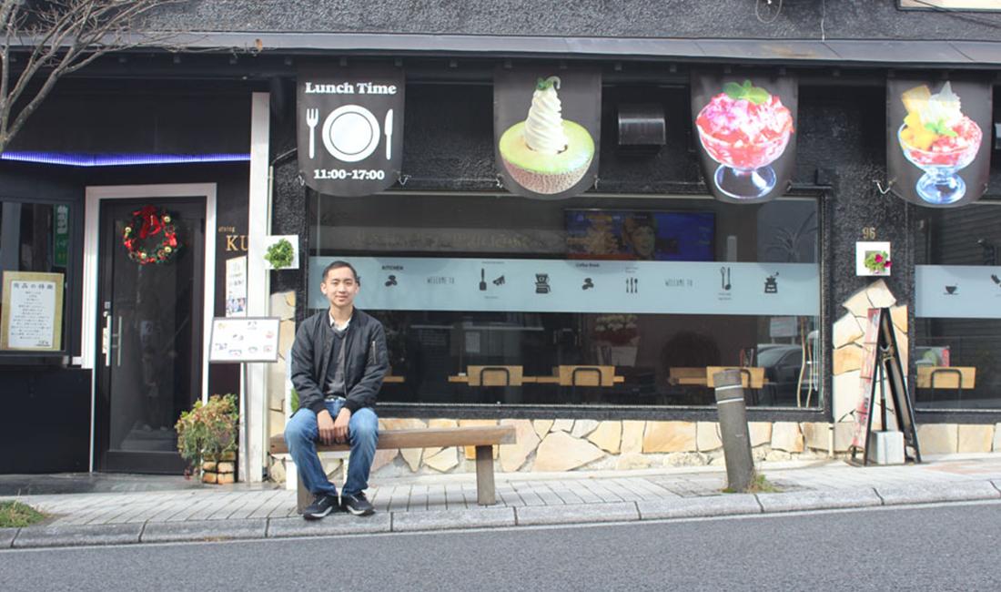 Brian To sits outside of a restaurant.