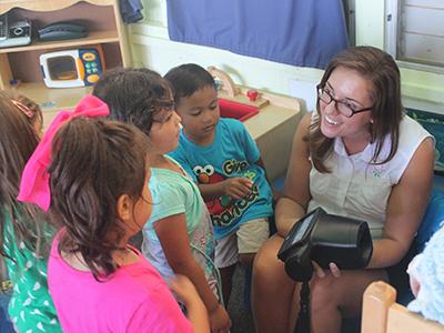 teacher with children crowded around her in a classroom 