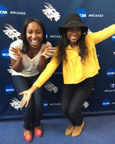 two students in front of a goat logo 