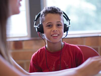 young child with headphones on and a red shirt 