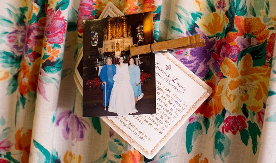 A family photo and a prayer pinned to a floral curtain.