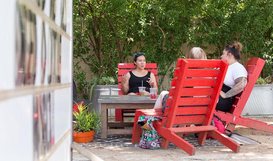 Victoria Rodriguez sits in a red patio chair with two friends.