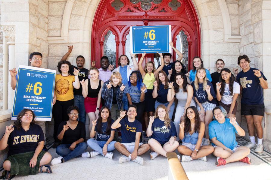 Students stand in front of the red doors with President Fuentes to celebrate the university #6 ranking