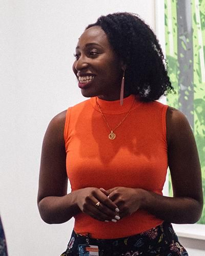 danielle samuel wearing an orange shirt and speaking to a class 